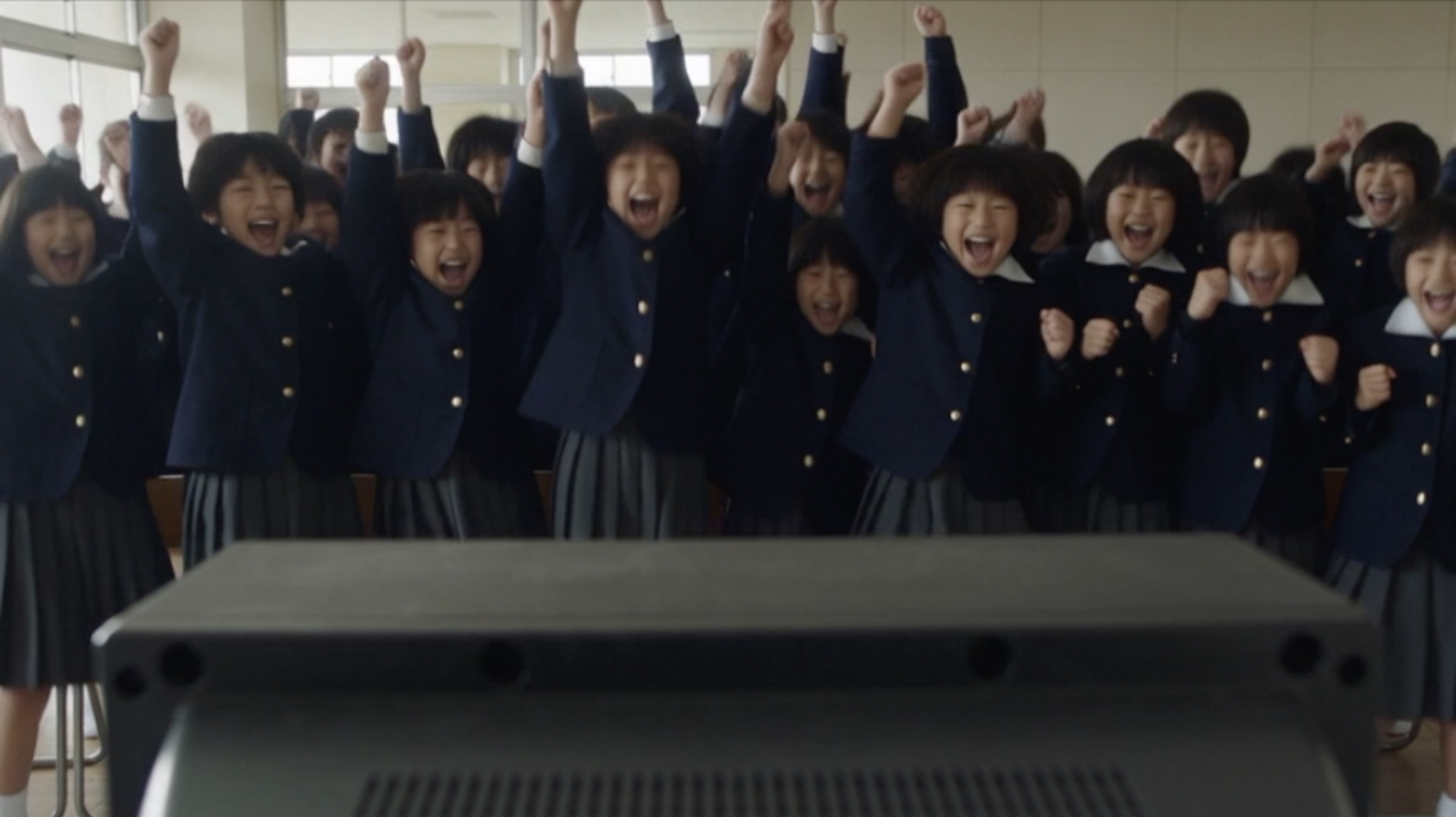 Kids and faculty cheering in the school TV room